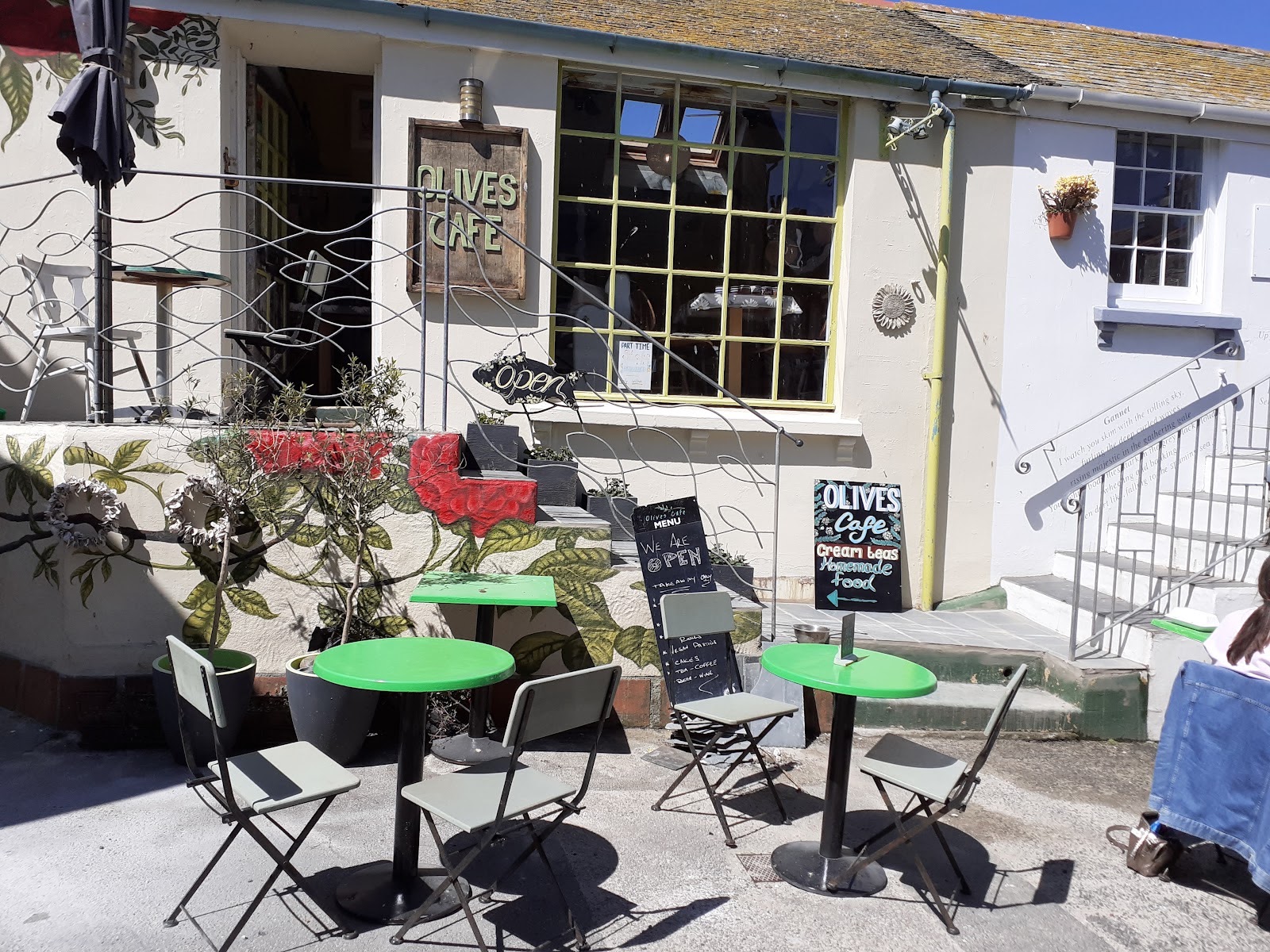 Olives Cafe exterior with green tables and mural